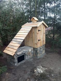 an outdoor fireplace built into the side of a wooded area with a roof made out of logs