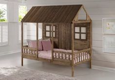 a small wooden house bed with pink pillows