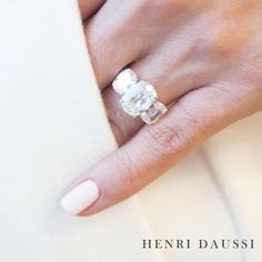 a woman's hand with a diamond ring on her left hand and white manicured nails