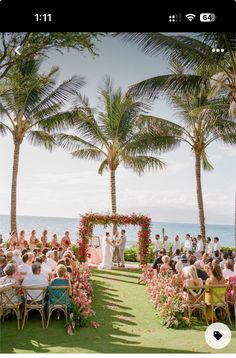 a wedding ceremony on the beach with palm trees and people sitting in chairs under them