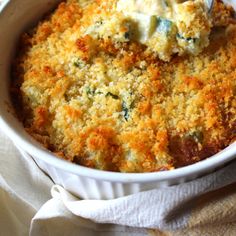 a casserole dish with broccoli and cheese in it on a white cloth