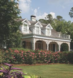 a large white house surrounded by flowers and trees