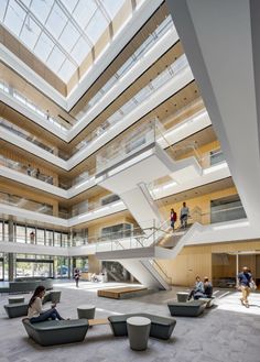 people are sitting on benches in the middle of a large building with skylights overhead