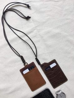 two leather tags attached to a cord on top of a white sheet with a cell phone