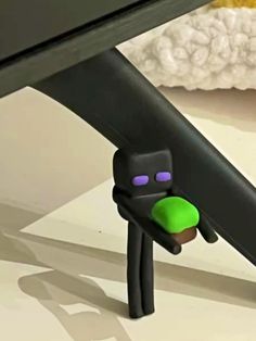 a black and green toy is under a desk