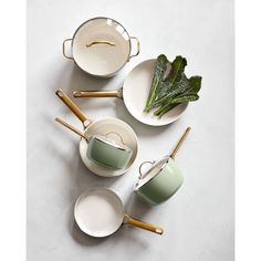 four white dishes with gold handles and green leafy greens in them, all on top of each other