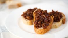 two pieces of bread topped with chili on top of a white plate