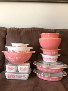 pink and white dishes stacked on top of each other in front of a brown couch