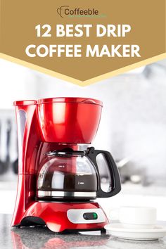 a red coffee maker sitting on top of a counter next to a cup and saucer