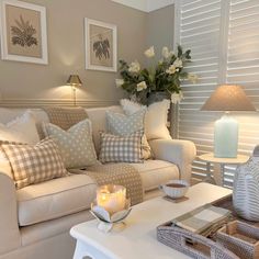 a living room filled with furniture and flowers on top of a white table in front of a window