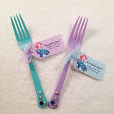 two plastic forks with tags attached to them sitting next to each other on a white surface