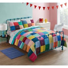 a bed with colorful bedspread and pillows in a room that has pink walls