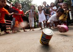 a can of beer sitting on the ground in front of some children playing with it