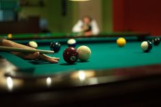 a pool table with several billards and two people in the background