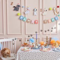 a dog sitting at a table in front of a wall with animal themed decorations on it