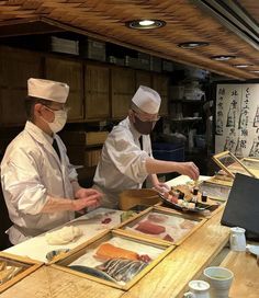 two chefs preparing sushi in a restaurant kitchen