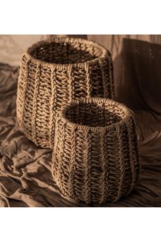 two woven baskets sitting on top of a bed