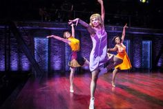 three women are dancing on stage in dresses