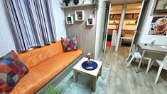 an orange couch sitting in the middle of a living room next to a table and chairs