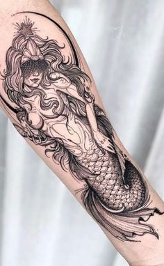 a black and white photo of a mermaid tattoo on the arm