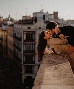 a man and woman kissing on top of a building