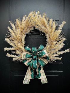 a wreath is hanging on a door with green and gold ribbons attached to the front