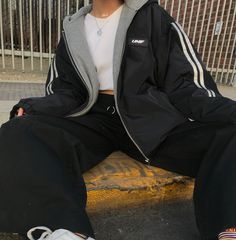 a woman sitting on top of a wooden bench wearing black pants and a white shirt