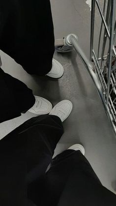 two people sitting on the ground with their feet up in front of a shopping cart