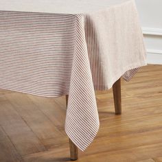 a table with a white and brown striped cloth on it, sitting in front of a wooden floor