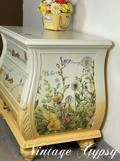 an old dresser painted with flowers and butterflies