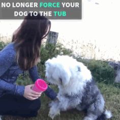 a woman kneeling down next to a dog with a pink cup in it's mouth