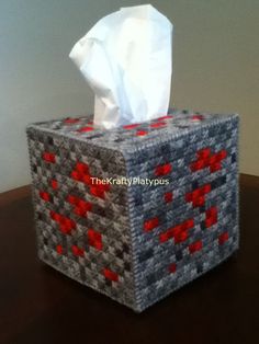 the tissue box is made out of knitted fabric and has red squares on it