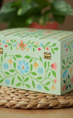 a decorative box sitting on top of a wicker table next to a potted plant