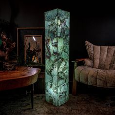 a large green marble column sitting in the middle of a living room next to a couch