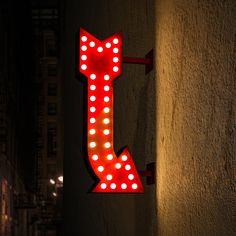 a neon sign that is lit up on the side of a building with lights all around it