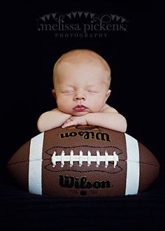 a baby laying on top of a football with the words mason written in white and black