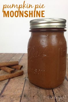 a jar filled with brown liquid sitting on top of a wooden table next to cinnamon sticks