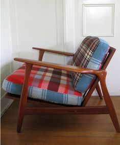 a plaid chair sitting on top of a wooden floor next to a white door and window