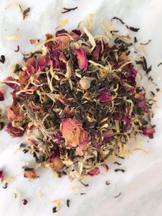 a pile of loose tea sitting on top of a white table next to dried flowers