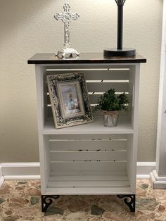 a white shelf with pictures and a cross on top