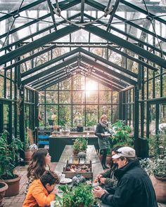 a group of people in a greenhouse surrounded by potted plants and other greenery