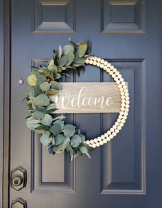 a welcome sign hanging on the front door with pearls and greenery around it's edges