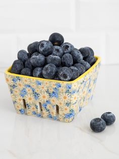 blueberries are in a yellow and white bowl