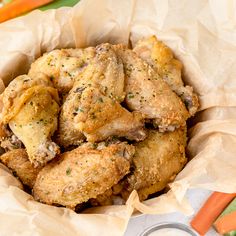 a basket filled with chicken wings covered in seasoning next to carrots and celery