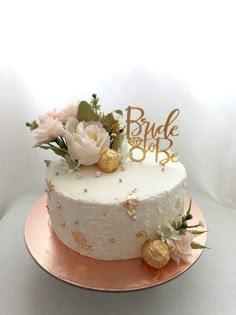 a white cake with gold decorations and flowers on top