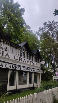 a white picket fence surrounding a building with a sign on it that says sea crafts