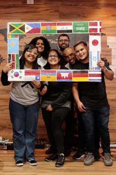 a group of people posing for a photo in front of a board with flags on it