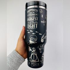 a person holding up a travel mug with harry potter characters on it