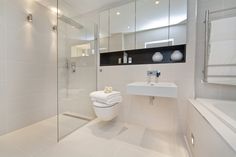 a bathroom with a toilet, sink, and shower stall in white tiled flooring