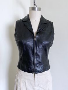 Incredible cropped leather vest. Features: a fitted style, zip closure, knit material, leather material, and a timeless style. Era: 90's Label: None Size Marked: None Estimated Size: S Material: Leather, Knit Blend with stretch Condition: Excellent Measurements: Measured Flat Chest: 16 1/2"-17 1/2"stretch Waist: 14 1/2"-15 1/2"stretch Length: 18" Measured flat, photographed on a size 6 form http://www.etsy.com/shop/wemovevintage All measurements are taken with the garment lying flat. Please see our policies for our point of measure :) Http://www.etsy.com/shop/wemovevintage/policy Please let us know if you have any questions! WEMOVEVINTAGE 6th Form, Black Leather Vest, Fitted Style, Vest Outfits, Leather Vest, Knitting Materials, Flat Chest, Leather Material, Womens Vest